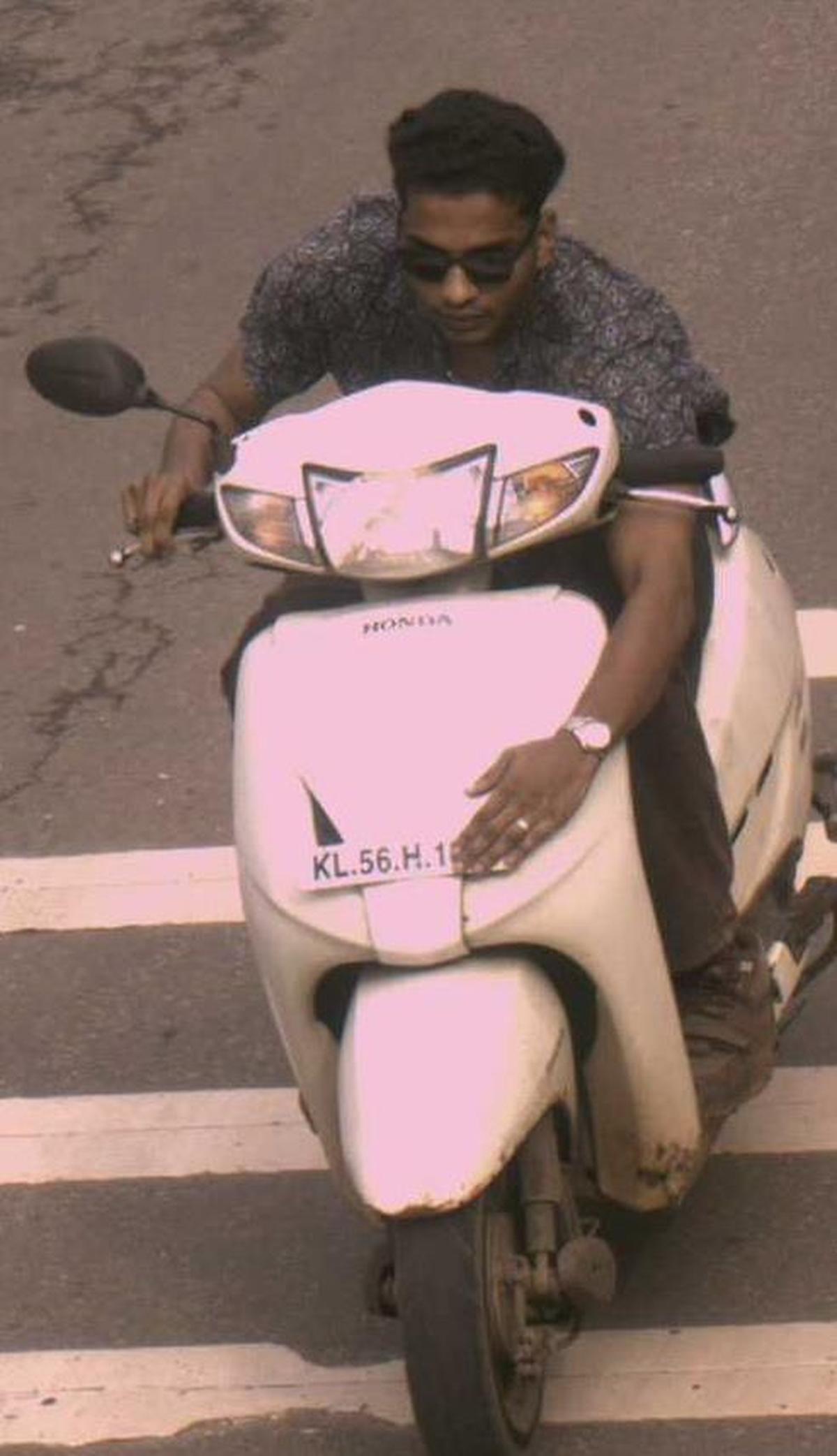 An AI camera visual accessed by the MVD and police shows a helmetless two-wheeler rider covering the number plate in front of the camera in Kozhikode district. 